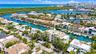 Aerial view showcasing a waterfront community with multiple residences featuring turquoise-water canals, mature palm trees, and lush landscaping throu