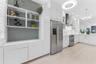 Kitchen featuring white cabinetry, stainless steel appliances, solid surface countertops, tile flooring, and custom wall-mounted shelving
