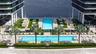 Outdoor terrace featuring two rectangular swimming pools, synthetic turf areas, paved stone decking, and manicured hedges
