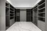 Walk-in closet featuring extensive built-in shelving, integrated hanging rods, custom cabinetry with pull-out drawers, and large-format tile flooring