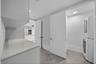 Utility area featuring stone-surface countertop, built-in cabinetry, large-format tile flooring, and dedicated laundry closet with stacked appliance c