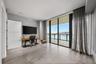 Floor-to-ceiling glass wall, large-format tile flooring, recessed ceiling lighting, and covered balcony featuring a glass panel railing