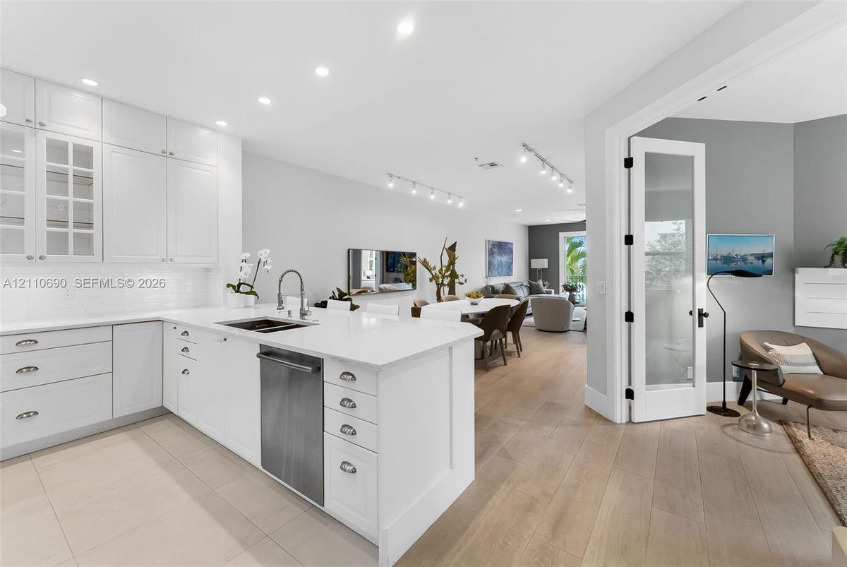 Kitchen featuring white shaker-style cabinetry, quartz countertops, a stainless steel dishwasher, recessed lighting, and wood-finish flooring
