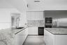 Kitchen featuring white flat-panel cabinetry, stone countertops with waterfall edge, full-height stone backsplash, stainless steel double wall ovens, 