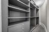 Custom organizational system featuring floor-to-ceiling cabinetry, integrated shelving, hanging rods, and built-in drawers with metallic hardware, set