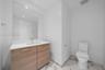 Vanity featuring a light wood-finish cabinet, white countertop with an integrated rectangular sink, large wall-mounted mirror, and tile flooring with 