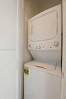 Stacked white laundry unit with dial controls and enclosed alcove setting
