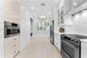 Kitchen featuring white Shaker-style cabinetry, stainless steel appliances, shiplap wall paneling, tile flooring, and interior window shutters