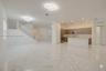 Open-concept interior featuring large-format polished stone flooring, custom wood-finish cabinetry, a central kitchen island, recessed ceiling lightin