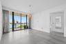 Floor-to-ceiling sliding glass doors, private balcony, large-format tile flooring, metallic pendant lighting, and wall-mounted mirror