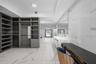 Custom built-in storage system with grey cabinetry, large-format tiled flooring, wall-to-wall vanity with dual sinks, and full-height tiled wall detai