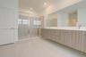 Floating dual-sink vanity with wood-grain cabinetry, expansive wall-to-wall mirror, and glass-enclosed shower with tiled surround