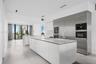 Contemporary kitchen featuring dual islands with stone-surface countertops, floor-to-ceiling cabinetry, integrated stainless steel appliances, and lar