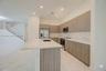 Kitchen featuring flat-panel wood-finish cabinetry, stone-surface countertops, a center island with an integrated sink, stainless steel appliances, an