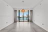 Large-format tile flooring, oversized sliding glass door, spherical glass pendant light, and balcony with water and city skyline backdrop