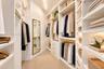 Walk-in closet featuring custom white cabinetry, adjustable shelving, integrated hanging rods, built-in storage drawers with metallic hardware, and a 