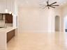 Open-concept interior featuring a textured stone accent wall, polished tile flooring, recessed lighting, four modern pendant lights, and a high ceilin