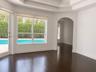 Tray ceiling with recessed lighting, wood-finish flooring, arched entryway, and large windows with exterior pool access