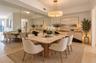 Dining area featuring floor-to-ceiling wall mirrors, a neutral stone-top table with a fluted wooden base, and a circular drum pendant light fixture wi
