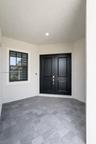 Covered entryway featuring double doors with matte black finish, stone-paver flooring, and a multi-pane window with dark trim