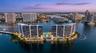 Waterfront high-rise complex featuring private swimming pools, palm-lined landscaping, and deep-water marina access