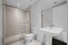 Walk-in shower with sliding glass doors, neutral tile surround, pedestal sink, chrome fixtures, and wall-mounted mirror