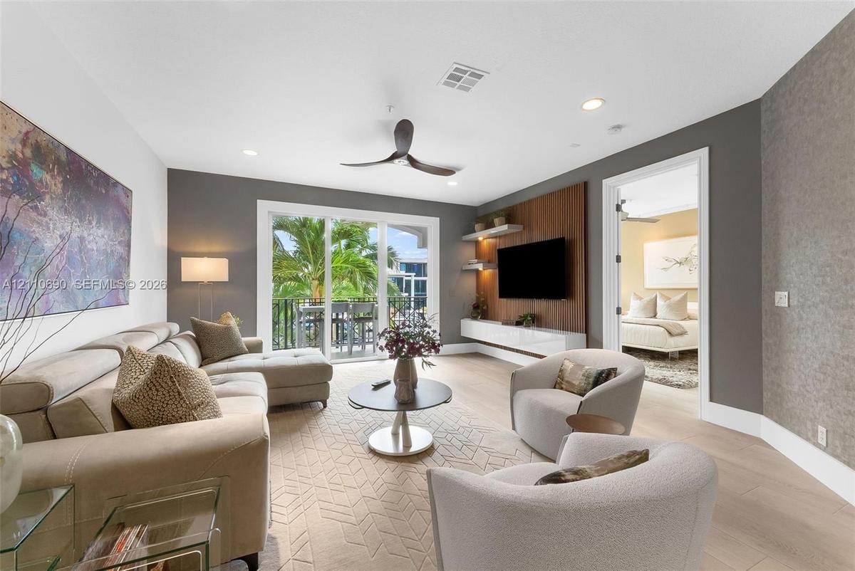 Living area featuring wood-finish flooring, a built-in media wall with wood paneling, floating cabinetry, recessed lighting, and sliding glass doors