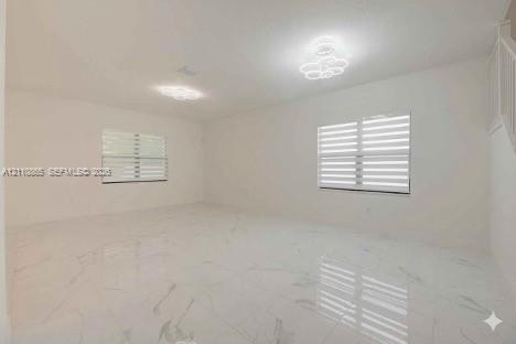 Large room featuring polished stone-finish tile flooring, dual modern floral-style flush-mount lighting fixtures, and dual-layered horizontal window s