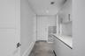 Utility area featuring large-format tile flooring, built-in light-tone cabinetry, stone-composite countertops, and integrated storage shelving