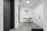Entry foyer featuring large-format grey tile flooring, minimalist white walls, recessed ceiling lighting, and a matte black elevator entrance