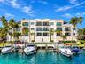 Multi-story building featuring stucco exterior, private recessed balconies with wrought-iron railings, integrated swimming pool, and deep-water boat s