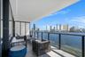 Covered balcony featuring tile flooring, glass-paneled railings with dark metal framing, and wide-reaching water and cityscape exposure
