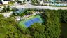 Tennis court with perimeter fencing, outdoor swimming pool, circular paved motor court, and canopy-covered recreation area