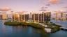 Waterfront residential complex featuring floor-to-ceiling glass facades, wraparound balconies, professional landscaping, and private island access