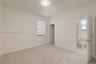Neutral-toned wall-to-wall carpeting, dual-tone roller shade, flush-mount ceiling lighting, and solid-core interior doors