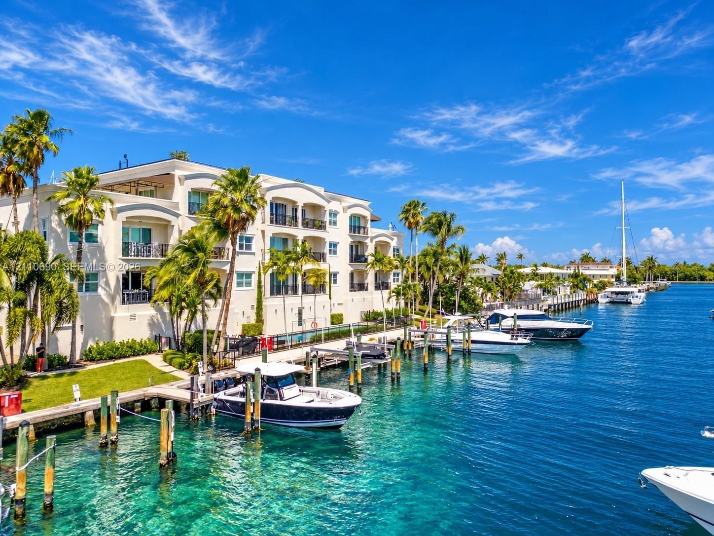 Waterfront residence featuring a three-story white stucco facade with arched windows and multiple balconies