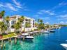 Waterfront residence featuring a three-story white stucco facade with arched windows and multiple balconies