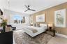 Bedroom featuring light wood-finish flooring, white plantation shutters, a contemporary ceiling fan, and adjustable track lighting