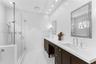 Double vanity featuring dark cabinetry, solid-surface countertops, recessed lighting, and a glass-enclosed walk-in shower with a multi-function shower