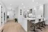 Kitchen featuring a quartz-topped island, white cabinetry with glass-panel accents, stainless steel appliances, shiplap detailing, and wood-finish flo