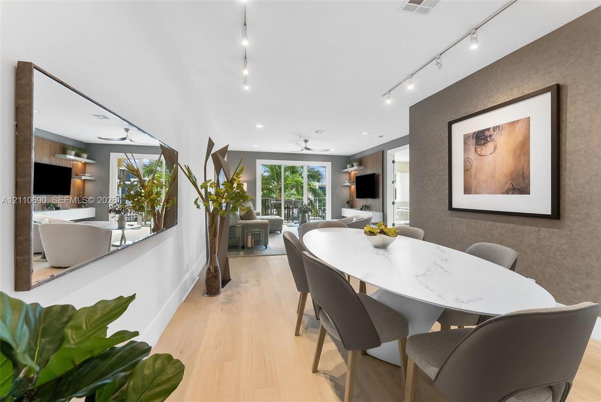 Dining area featuring wood-finish flooring, a wall-mounted oversized mirror, textured accent wall, and adjustable track lighting