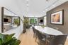 Dining area featuring wood-finish flooring, a wall-mounted oversized mirror, textured accent wall, and adjustable track lighting