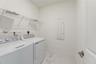 Utility area featuring white-finish tile flooring, wall-mounted wire shelving, and a recessed electrical panel