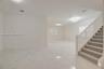 Open-concept interior featuring large-format polished tile flooring, a staircase with white balusters and neutral carpeting, multi-tier crystalline ch