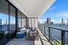 Expansive covered terrace featuring floor-to-ceiling glass panel doors, concrete-finish flooring, and a sleek glass-paneled railing with black framing