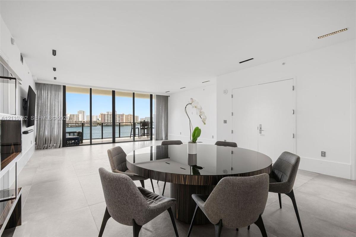 Open-concept interior featuring large-format tile flooring, floor-to-ceiling glass panel windows, integrated recessed lighting, and a private balcony