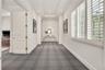 Hallway featuring recessed ceiling lighting, tray ceiling details, plantation shutters, and patterned carpeting