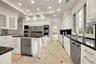 Kitchen featuring white cabinetry, dark stone countertops, stainless steel appliances, a central island with a built-in beverage refrigerator, and sto