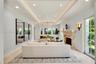 Living area featuring a tray ceiling with recessed lighting, carved stone fireplace mantel, wall-to-wall mirrors, light-toned stone flooring, and mult