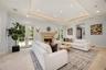 Tray ceiling with recessed lighting, carved stone fireplace surround, tile flooring, and dual sets of French doors with glass panes